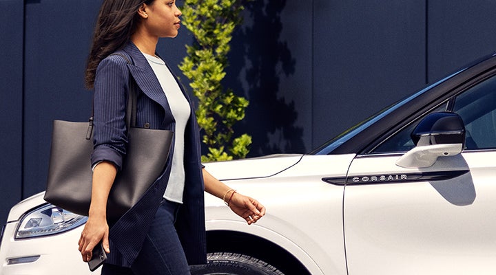 A woman approaches a 2024 Lincoln Corsair® SUV while holding a smartphone. | Griffin Lincoln in Tifton GA