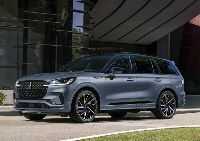 A gray 2025 Lincoln Aviator® SUV is parked outside a modern building showcasing the driver’s side of the vehicle. | Griffin Lincoln in Tifton GA