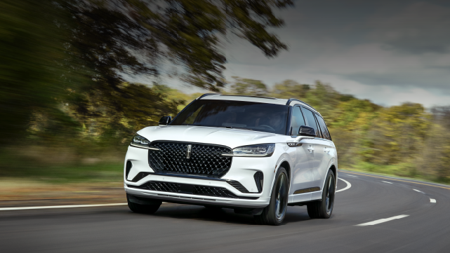 A white 2025 Lincoln Aviator® SUV is being driven down a road lined with trees. | Griffin Lincoln in Tifton GA