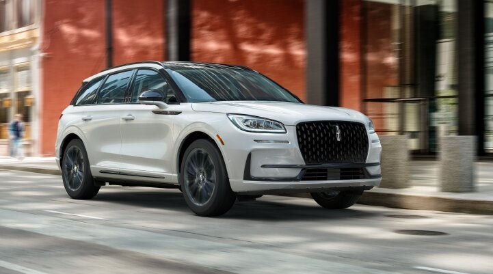 A white 2025 Lincoln Corsair® SUV with the Jet Appearance Package is being driven through a city.| Griffin Lincoln in Tifton GA