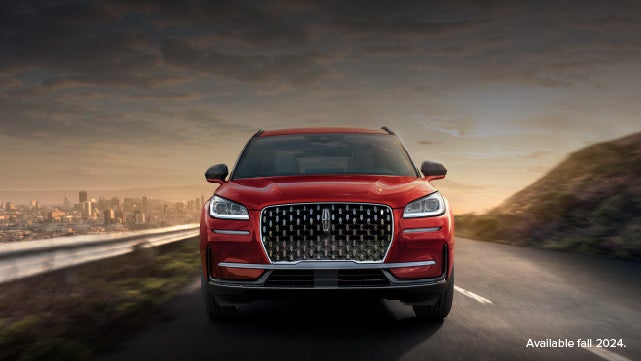 A 2025 red Lincoln Corsair® SUV is being driven down a road at sunset. | Griffin Lincoln in Tifton GA