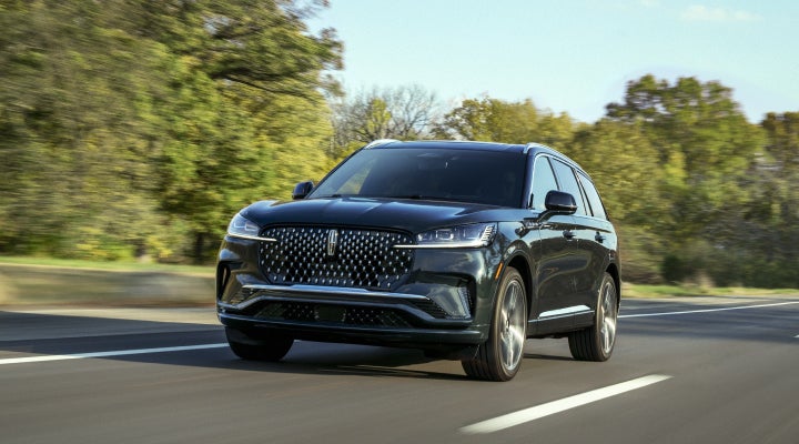 A 2026 Lincoln Black Label™ Aviator® SUV is being driven down a road lined with trees. | Griffin Lincoln in Tifton GA