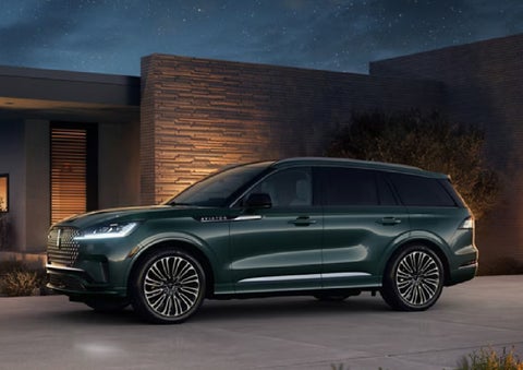 A green 2027 Lincoln Aviator® SUV is parked outside a contemporary home. | Griffin Lincoln in Tifton GA