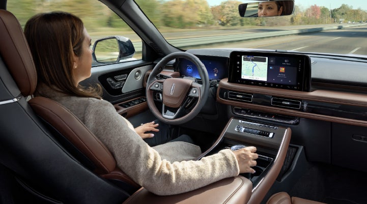 A 2027 Lincoln Aviator® SUV is being driven hands-free on a highway lined with trees. | Griffin Lincoln in Tifton GA
