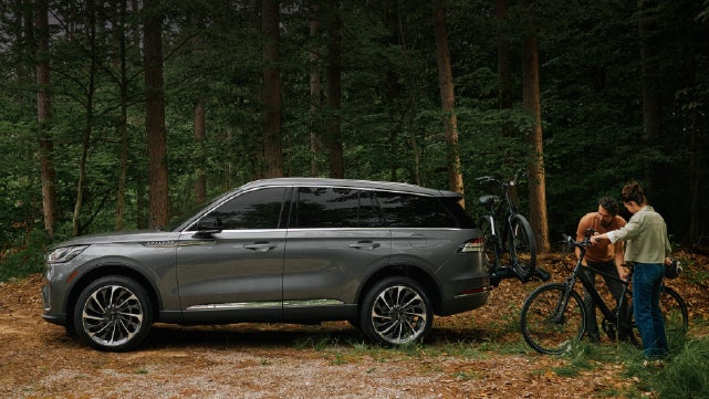 A father and son load e-bikes on a bike rack attached to a 2027 Lincoln Aviator® SUV. | Griffin Lincoln in Tifton GA