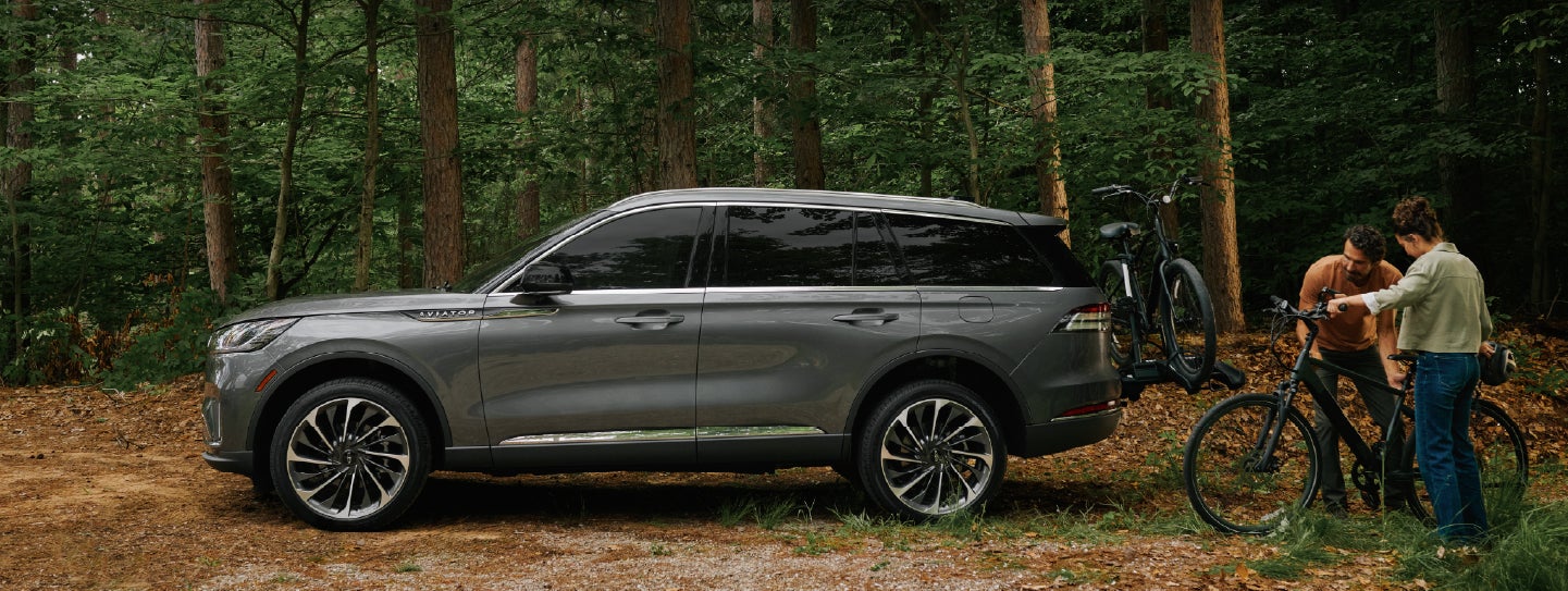 A father and son load e-bikes on a bike rack attached to a 2027 Lincoln Aviator® SUV. | Griffin Lincoln in Tifton GA